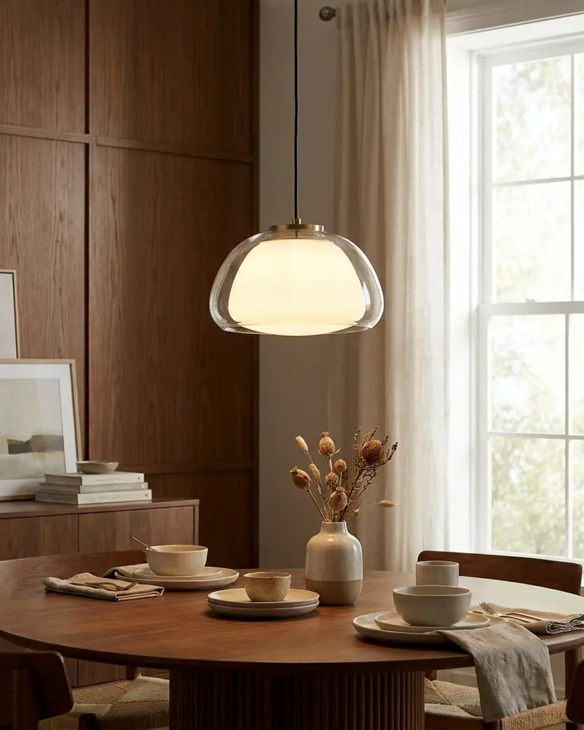 Lámpara colgante de vidrio transparente y difusor dorado en comedor